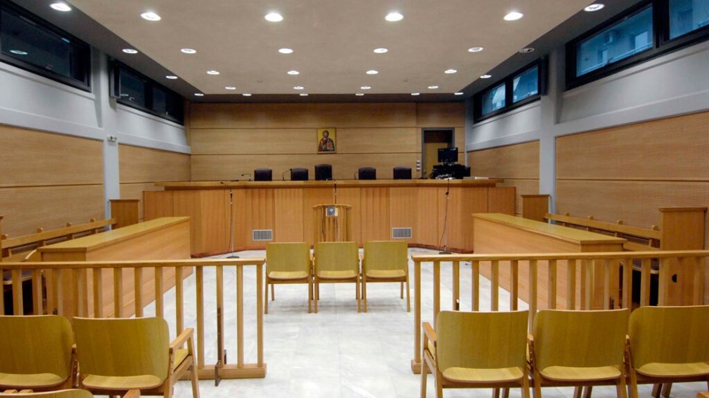 Αίθουσα δικαστηρίου με καθίσματα αριστερά και δεξιά, διάδρομο στη μέση και η έδρα στο βάθος