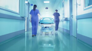Διάδρομος νοσοκομείου. Δύο νοσηλεύτριες κρατούν ένα φερόμενο κρεβάτι.