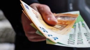 Χρήματα σε χαρτονομίσματα των 50 και 100 ευρώ με χέρι που τα κρατά