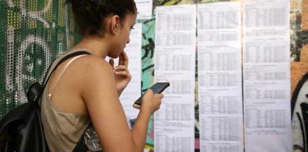 διαγωνιζόμενοι σε Πανελλαδικές Εξετάσεις διαβάζει τα αποτελέσματα που έχουν αναρτηθεί στο τοίχο του σχολείου