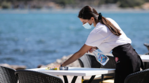 γυναίκα σερβιτόρα καθαρίζει τραπέζι σε παραλία