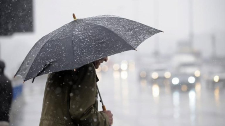 Άνδρας που κρατάει μαύρη ομπρέλα σε συνθήκες βροχής