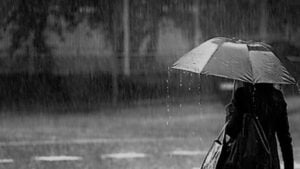 Βροχερός καιρός με γυναίκα που κρατάει μαύρη ομπρέλα