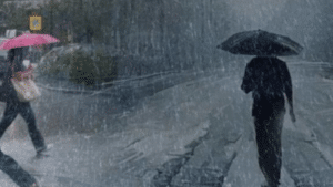 Άνθρωποι με μαύρα ρούχα περπατάνε κρατώντας ομπρέλα την ώρα καταιγίδας