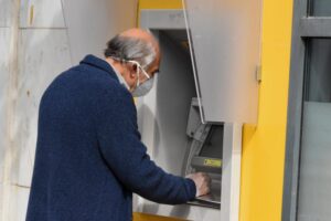 ηλικιωμένος βρίσκεται μπροστά από ΑΤΜ και επιχειρεί να βγάλει χρήματα με την κάρτα του
