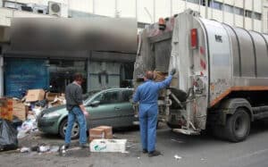 εργάτες καθαριότητας αδειάζουν κάδους απορριμμάτων σε απορριμματοφόρο 