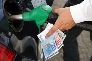 άνθρωπος βάζει βενζίνη στο ρεζερβουάρ του αυτοκινήτου ενώ ταυτόχρονα κρατά χαρτονομίσματα των 20, 10 και 5 ευρώ. 