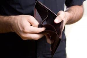 ένας άντρας κρατά ανοιγμένο ένα άδειο πορτοφόλι
