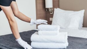 καμαριέρα ακουμπά πετσέτες μπάνιου σε κρεβάτι ξενοδοχείου