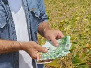 ένας αγρότης βρίσκεται σε χωράφι και κρατά χαρτονομίσματα