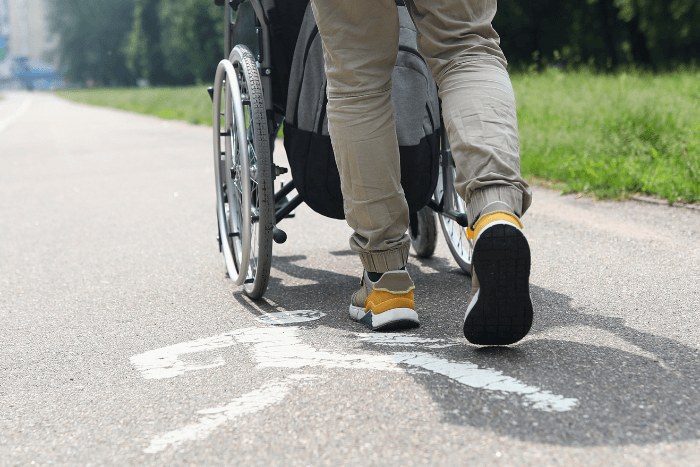ένας άντρας βγάζει βόλτα με αναπηρικό αμαξίδιο άντρα με κινητικά προβλήματα.