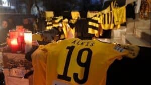 Κίτρινη φανέλα της ποδοσφαιρικής ομάδας "Άρης" Θεσσαλονίκης, προς τιμήν του δολοφονημένου Άλκη Καμπανού