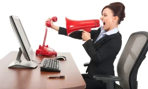 μια υπάλληλος γραφείου κρατά το ακουστικό ενός τηλεφώνου και με το άλλο χέρι κρατά μια ντουντούκα και φωνάζει