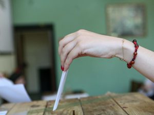 ένα γυναικείο χέρι ρίχνει ψηφοδέλτιο σε κάλπη