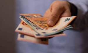 ένα χέρι προτάσσει χαρτονομίσματα των 10, 20 και 50 ευρώ