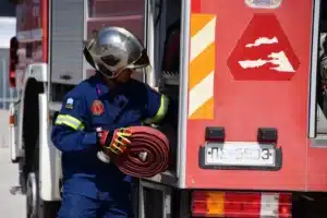 πυροσβέστης έξω από πυροσβεστικό κόκκινο όχημα εν ώρα εργασίας