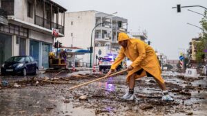 Γυναίκα με αδιάβροχη κίτρινη στολή καθαρίζει δρόμους εν μέσω κακοκαιρίας