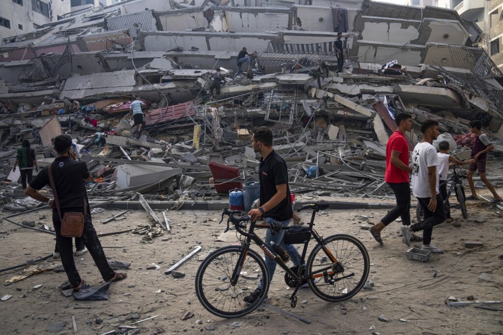 Πόλεμος Ισράηλ. Ένας ποδηλάτης και άλλα α΄τομα βλέπουν μπορστά τους ένα καετστραμένο κτήριο. 