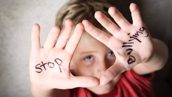 Μικρό αγοράκι με κόκκινη μπλούζα με ανοιχτές παλάμες που αναγράφουν "Stop Bullying"
