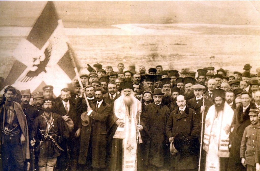 Η επίσημη φωτογραφία από την ανακήρυξη της Αυτονομίας στο Αργυρόκαστρο το 1914, με τον Γεώργιο Χρηστάκη-Ζωγράφο, επισκόπους, στρατιωτικούς και πολίτες μπροστά από τη σημαία της Βορείου Ηπείρου.