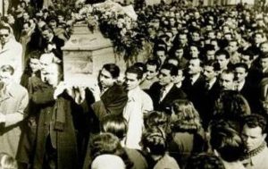 Η σορός του Κωστή Παλαμά μεταφέρεται μέσα από το πλήθος στην κηδεία του στο Α’ Νεκροταφείο Αθηνών, τον Φεβρουάριο του 1943, σε μια τελετή που εξελίχθηκε σε μαζική εκδήλωση εθνικής συγκίνησης και αντίστασης κατά την περίοδο της Κατοχής.